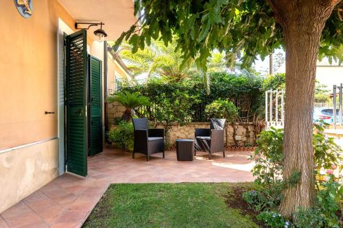 a patio with chairs and a tree next to a house at Villa Aura in Marina di Modica