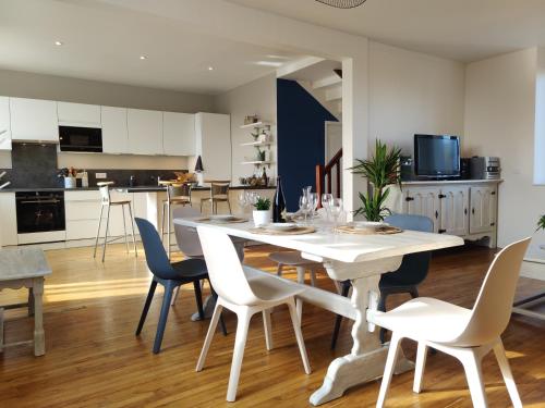 una cucina e una sala da pranzo con tavolo e sedie bianchi di Maison wifi jardin arboré pointe du Raz a Plogoff