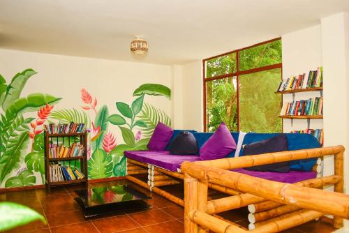 a living room with a purple couch and a mural at Spondylus Lodge in Ayampe