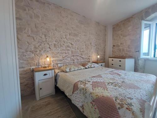 a bedroom with a bed and a stone wall at Bobelino in Povlja