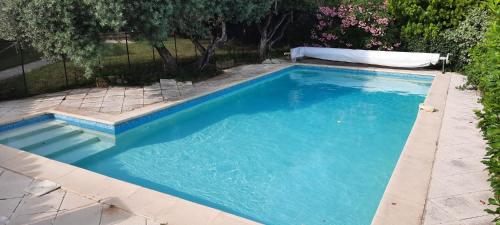une piscine avec de l'eau bleue dans une cour dans l'établissement Maison le Pastaga, à Caromb