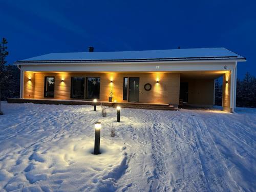 une maison éclairée la nuit dans la neige dans l'établissement Brand New! Villa Moon, à Rovaniemi