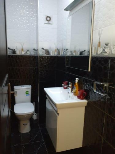 a bathroom with a white toilet and a sink at Appartement Anis in Agadir