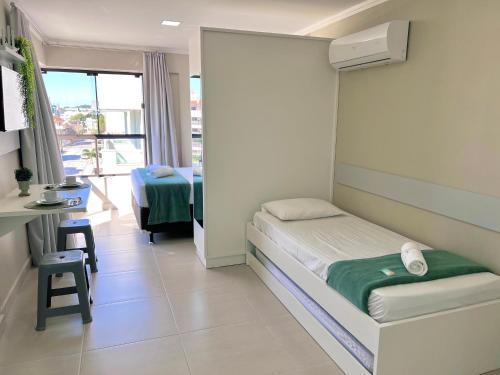 a bedroom with a bed and a desk and a window at Bella Catarina Bombinhas in Bombinhas