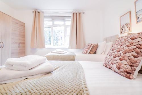 een witte kamer met 2 bedden en witte handdoeken bij 2 Bed Apartment - Great Location in Hendon