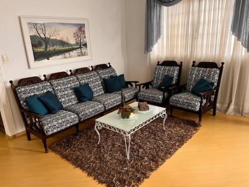 a living room with a couch and two chairs and a table at Triplex 5 min do Jardim Botânico in Curitiba