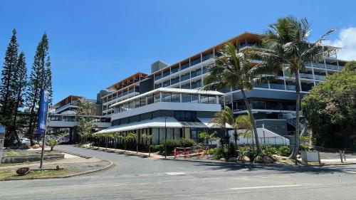 a large building with palm trees in front of a street at F1 standing vue mer Anse Vata in Noumea