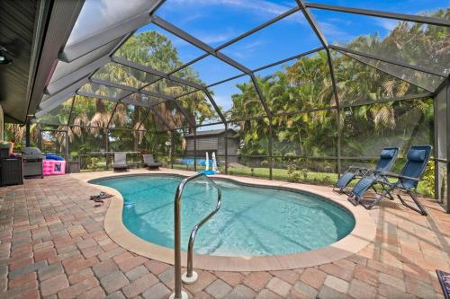 a swimming pool with two chairs and an umbrella at Sunny Oasis Getaway -Heated Pool-Mini Golf-Near Beach in Nokomis