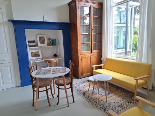 a living room with a yellow couch and a table at Villa Benvenuto in Dieren