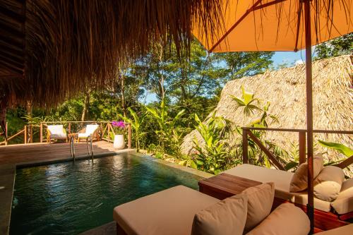 a pool in a resort with chairs and an umbrella at Tewimake Hotel in Santa Marta