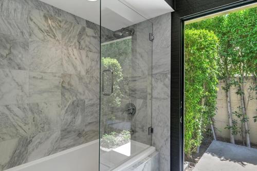 a glass shower in a bathroom with a window at Canyon Palms Estate- Ultra-Luxe, Pool, Spa, Firepit, Outdoor Kitchen & More in Palm Springs