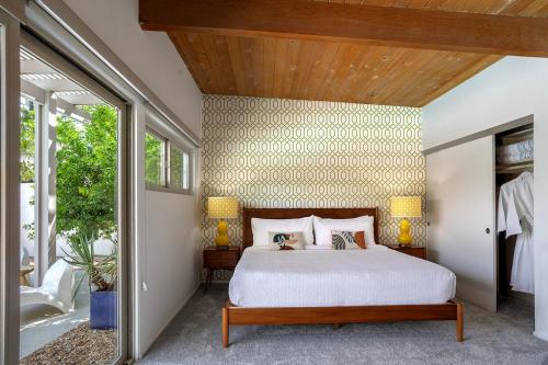 a bedroom with a bed and a wooden ceiling at On The Rox- Luxury Refreshing Mid-Century Mod- Pool, Spa, Firepit, Outdoor Kitchen & More in Palm Springs