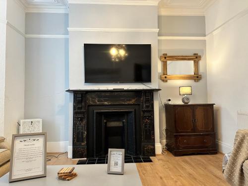 a living room with a fireplace with a flat screen tv over it at Victorian/modern house in Newport