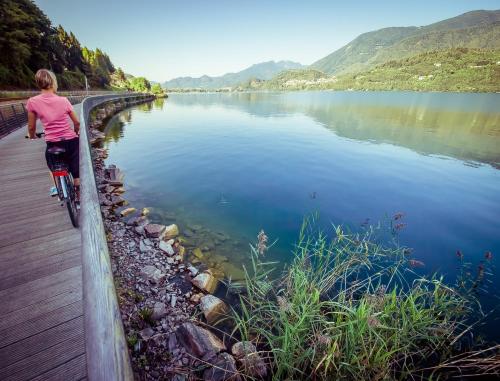 uma mulher a andar de bicicleta ao lado de um corpo de água em Appartamento lake-side em Calceranica al Lago