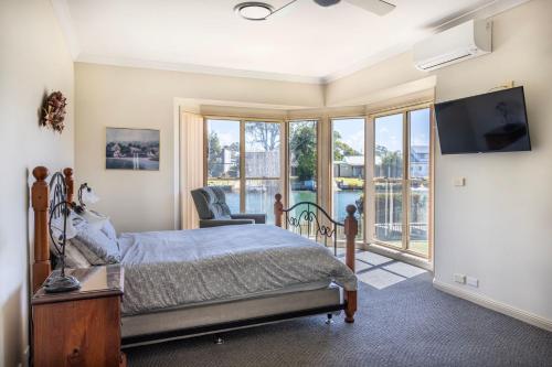 a bedroom with a bed and a large window at Cormorant Waterfront Home in Sussex Inlet