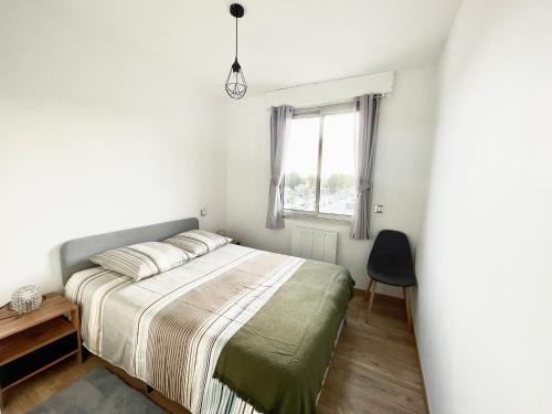 ein Schlafzimmer mit einem Bett und einem Fenster in der Unterkunft Appartement La Guignette in La Rochelle