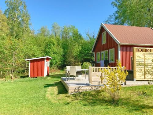 a small red house with a deck and a table at The Blomsholm Cabin in Strömstad