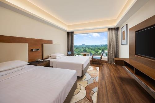 ボーパールにあるCourtyard by Marriott Bhopalのベッド2台、薄型テレビが備わるホテルルームです。