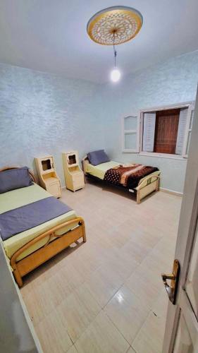 1 Schlafzimmer mit 2 Betten und 2 Stühlen in der Unterkunft Sahrawi Abdo 2 in Er Rachidia