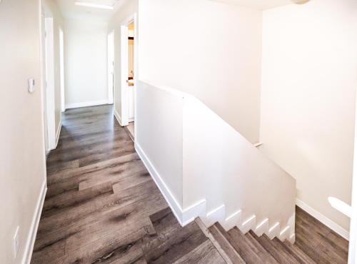 a white staircase in a hallway with wood floors at Large chic 5-bedroom 3 bathroom clost to Downtown LA in Los Angeles