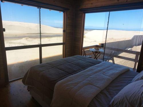 um quarto com uma cama e vista para o deserto em Cabana das Dunas beira mar em Jaguaruna