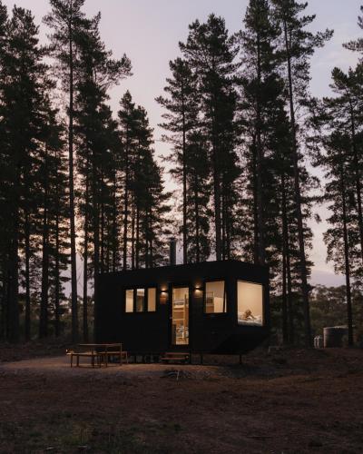 a small black house in the middle of a forest at CABN Kuitpo Forest in Kuitpo
