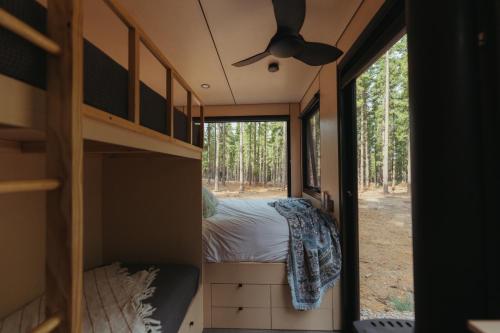 a bedroom in a tiny house with a bed and a window at CABN Kuitpo Forest in Kuitpo