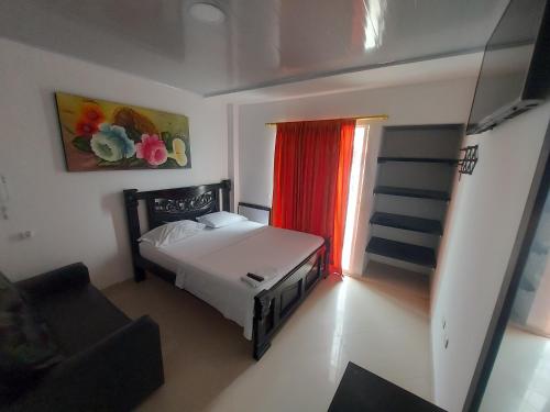 ein Schlafzimmer mit einem Bett und einem Fenster mit einem roten Vorhang in der Unterkunft HOTEL CASA BLANCA in Aguachica