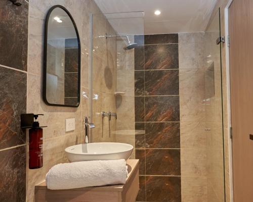 y baño con lavabo y ducha con espejo. en Elemont Hotel, en Medellín