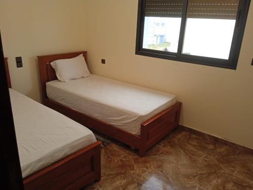 two beds in a small room with a window at Appartement familial 1 in Oualidia