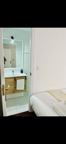 baño blanco con lavabo y cama en El sauce de la calle Sinagoga Precioso apartamento en el centro de La Coruña, en A Coruña