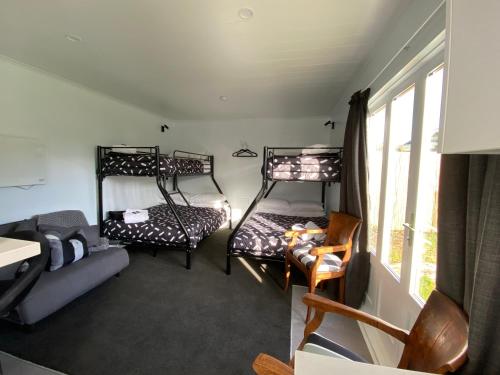 a room with three bunk beds and a couch at Methven Retreat Tiny House in Methven