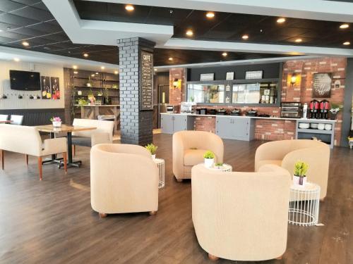 a restaurant with white chairs and tables and a bar at Merit Hotel & Suites in Fort McMurray
