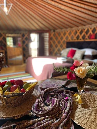 a table with a bowl of fruit and a bowl of flowers at Glamping montain experience in São Joaquim