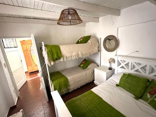 1 dormitorio con 2 camas y mantas verdes en Casa divina temporaria en Tafí Del Valle ,pleno centro en Tafí del Valle