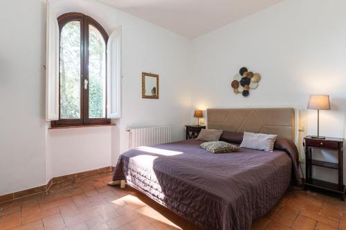 1 dormitorio con cama y ventana en Antico Podere Il Bugnolo, en Poggibonsi