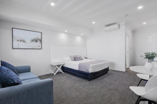 a bedroom with a bed and a couch and a table at Shellharbour Village Motel in Shellharbour