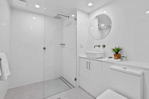 a white bathroom with a sink and a mirror at Shellharbour Village Motel in Shellharbour