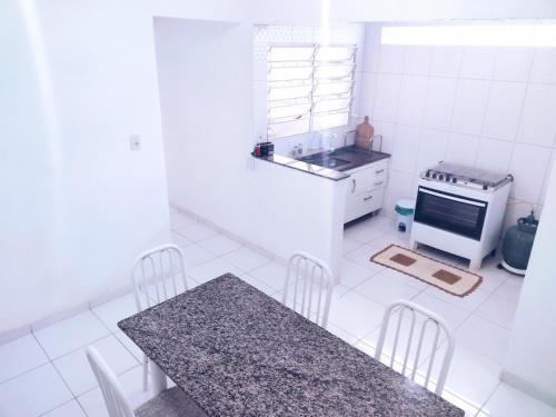 une cuisine blanche avec une table et une cuisinière dans l'établissement Casa na praia para até 10 pessoas, à São Sebastião