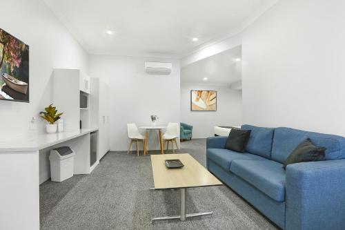 a living room with a blue couch and a table at Shellharbour Village Motel in Shellharbour