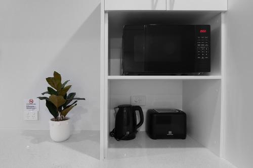 a microwave in a kitchen with a coffee maker and a toaster at Shellharbour Village Motel in Shellharbour