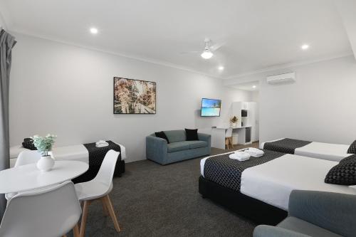 Habitación de hotel con 2 camas y mesa en Shellharbour Village Motel, en Shellharbour