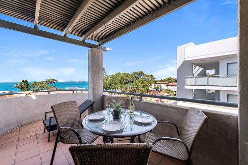 a table on a balcony with a view of the ocean at Peninsula Waters Unit 14 Soldiers Point Road 2 in Soldiers Point