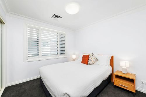 a white bedroom with a bed and a window at Peninsula Waters Unit 14 Soldiers Point Road 2 in Soldiers Point