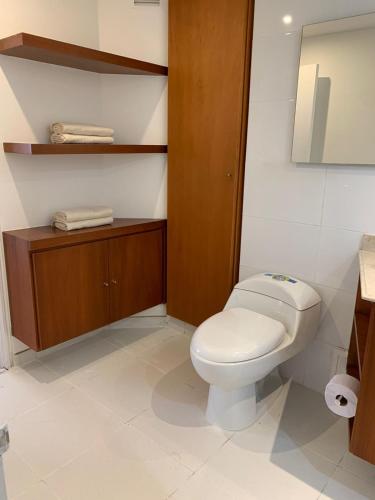 ein Badezimmer mit einem weißen WC und einem Spiegel in der Unterkunft HERMOSO APARTAMENTO SANTA BARBARA in Bogotá