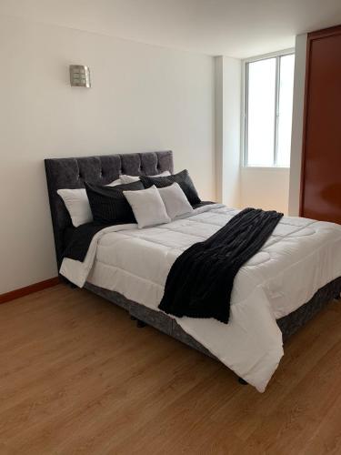 uma cama grande com lençóis e almofadas preto e branco em HERMOSO APARTAMENTO SANTA BARBARA em Bogotá