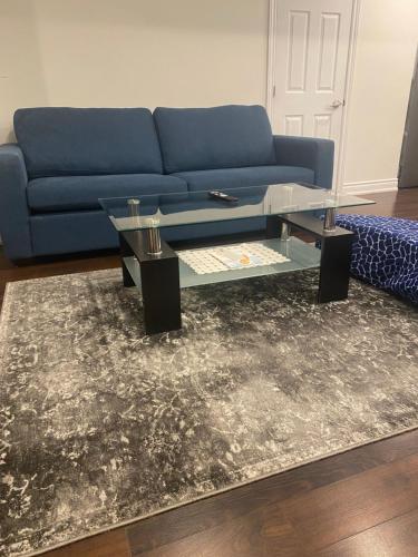 a living room with a blue couch and a glass coffee table at Beautiful Lower level 2 bedroom aprt in Toronto