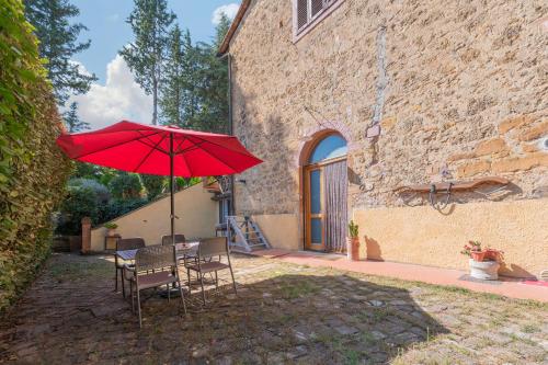 a table with a red umbrella in front of a building at Antico Podere Il Bugnolo in Poggibonsi