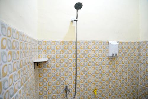 a bathroom with a shower with a tile wall at Haura syariah home stay in Bandar Lampung