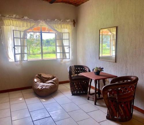 Zimmer mit einem Tisch, Stühlen, einem Tisch und einem Fenster in der Unterkunft Casa de campo cerca de Guadalajara. in San Isidro Mazatepec